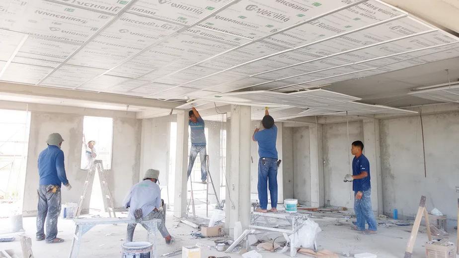 Workers installing Vinceiling moisture-resistant ceiling panels in a modern construction site in Vietnam.